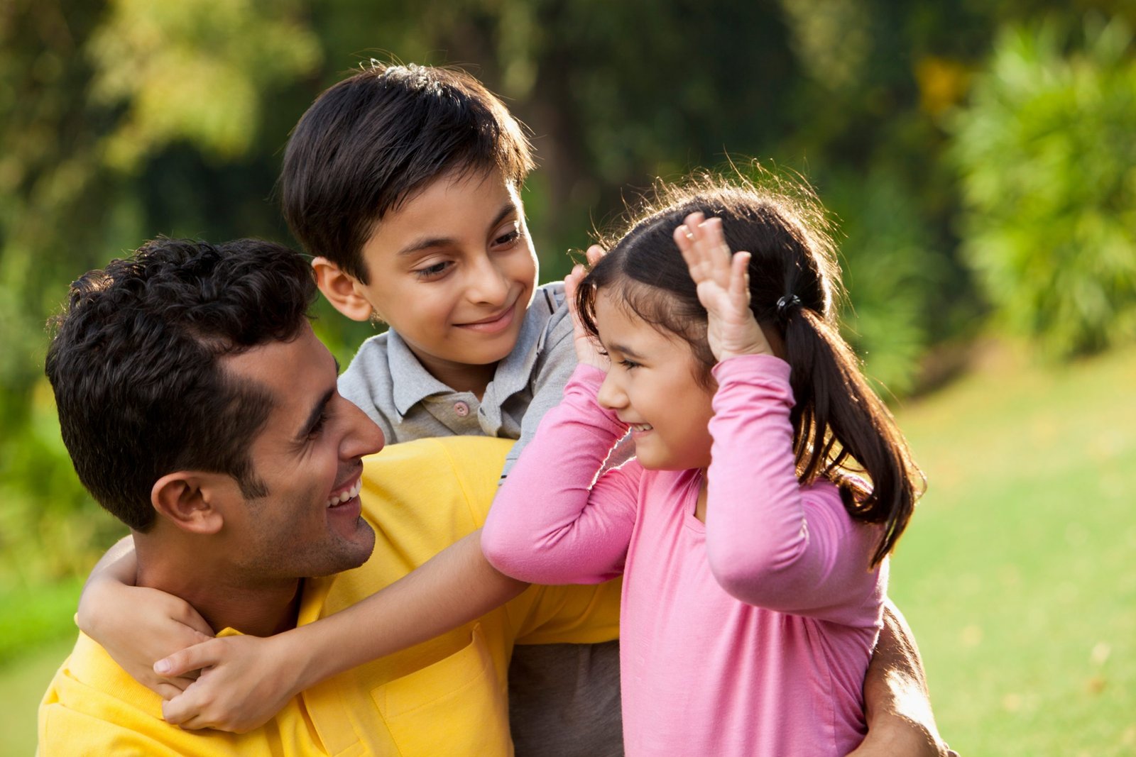 Father and young boy and girl outside in the grass