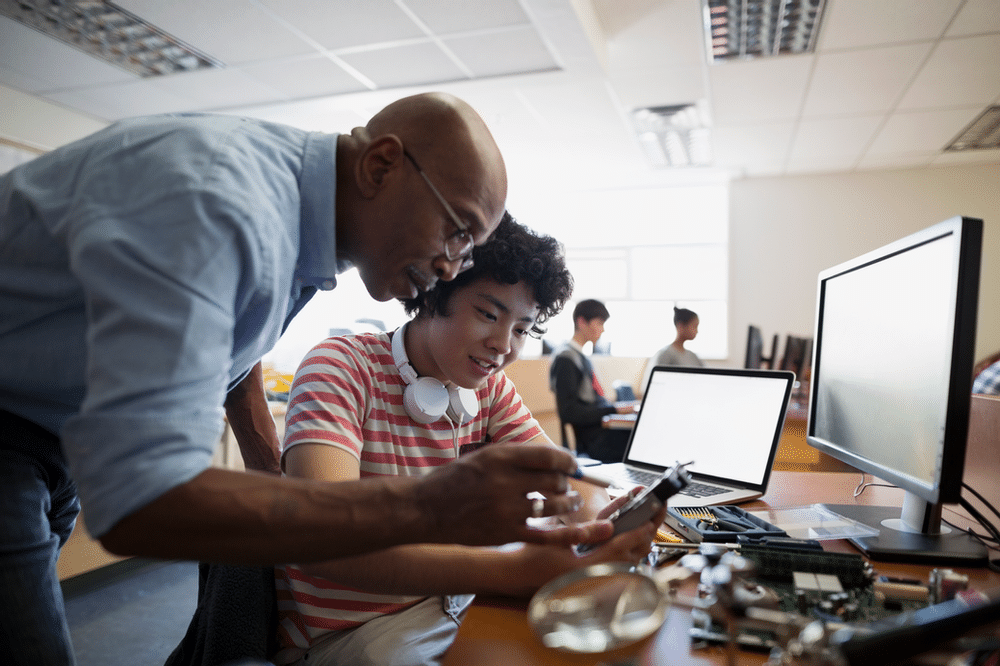 Teacher helping student over computer screen
