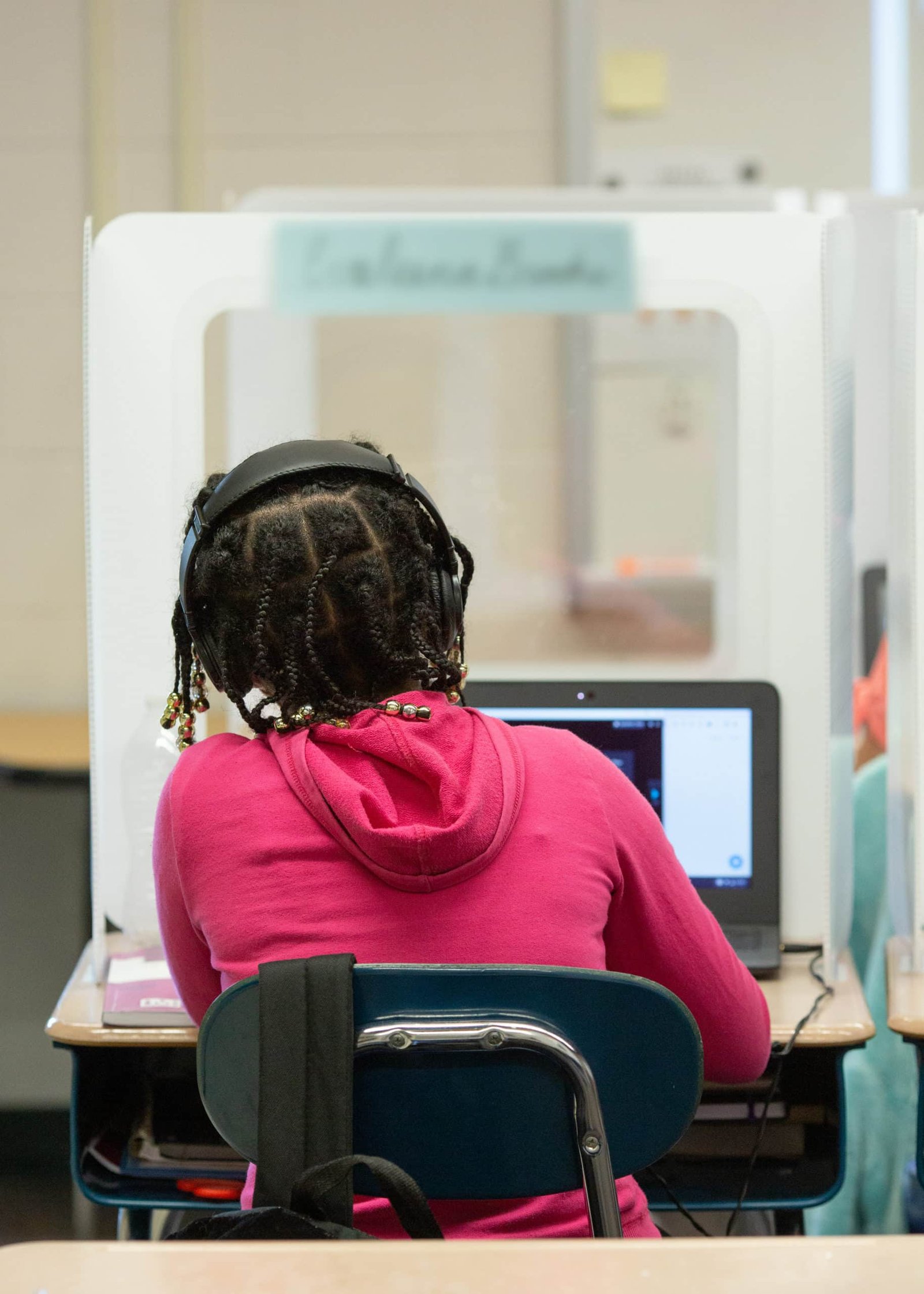 Fifth-grade girl at computer behind protection shield