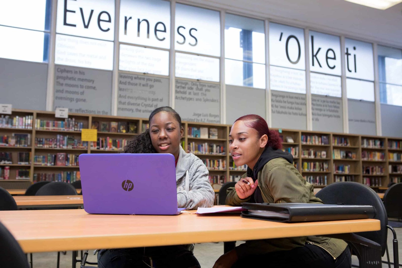 Two high school girls at computer in library