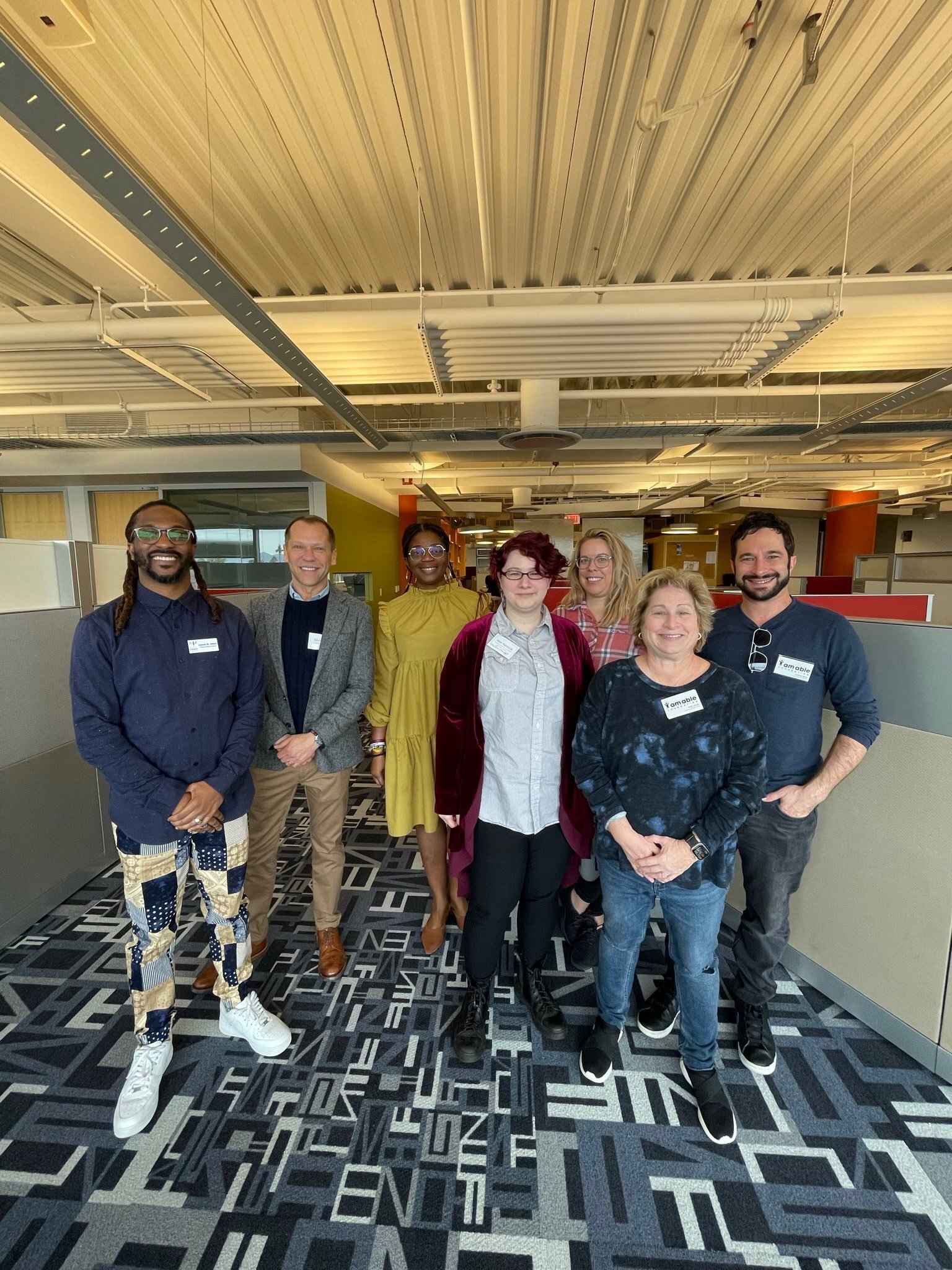 A diverse group of professionals standing together in a modern office environment, engaged in conversation.