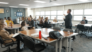 Adults sitting at tables and a principal leading a discussion