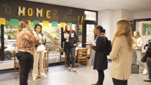 A group of 5 adults standing in a school hallway talking