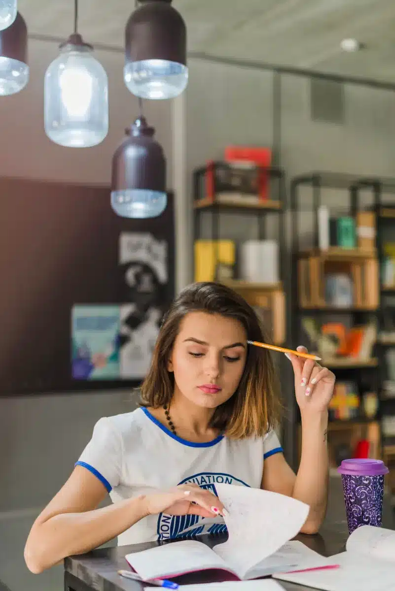 A young girl reading a book with her pencil in her hand