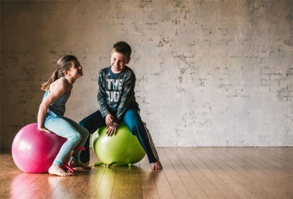 Two children sitting on yoga balls