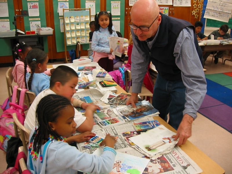 Teacher standing over two students at a desk