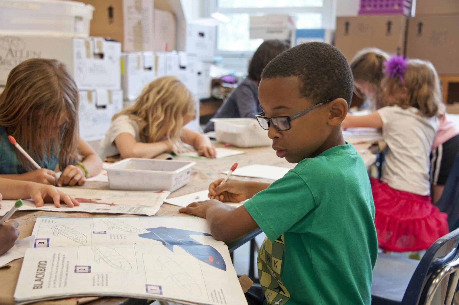 Boy in green t-shirt writing at a desk