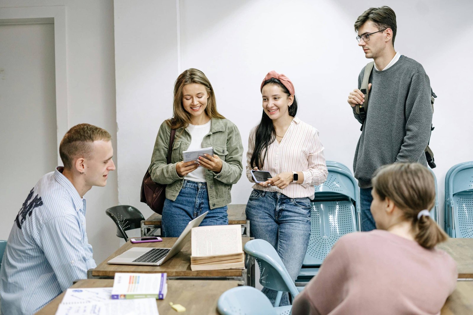 Five adults standing around a table chatting.