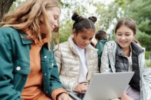 Three students sitting around one laptop