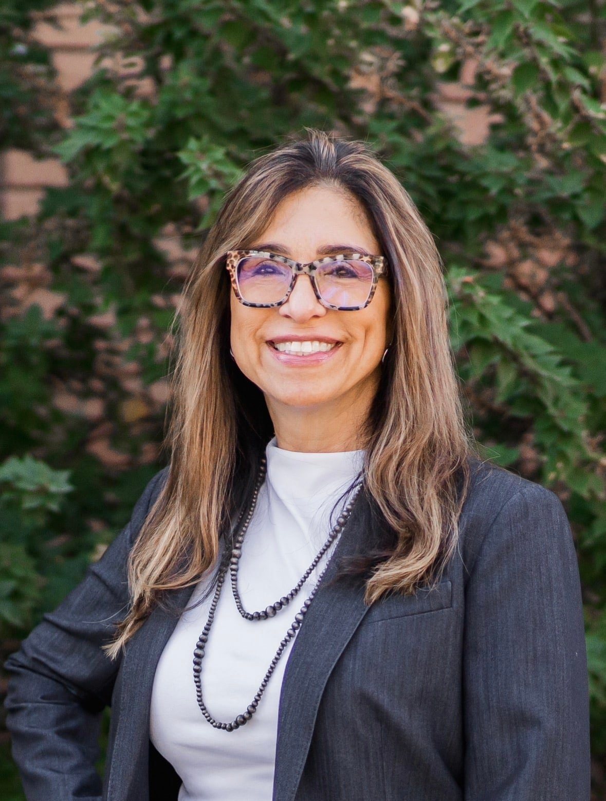 A woman wearing glasses and a suit jacket, exuding professionalism and confidence.